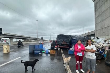 Janaína da Silveira, à esquerda, e Tatiane Marinho enfrentam o risco e se abrigam à beira da rodovia, com pertences e animais — Foto: Credito: Fernanda Canofre/Credito: Fernanda Canofre