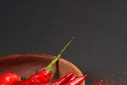 Web // pimenta Large red chili and chilli powder served on wooden bowk isolated on a black background